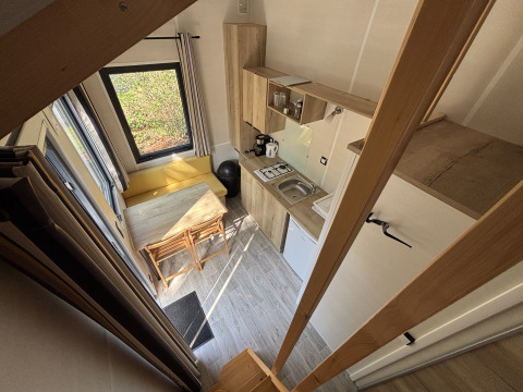 Udsigt ovenfra af et kompakt tiny house med køkken, spisebord og store vinduer i Recreation Park de Paalberg.