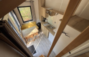 Vista desde arriba de una tiny house con cocina, comedor y ventanas en Recreation Park de Paalberg, Países Bajos.