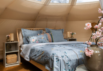 Gemütlich eingerichtetes Schlafzimmer im Lotus Belle Zelt bei De Achterste Hoef, mit blauer Bettwäsche.