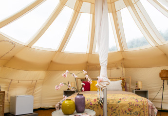 Innenraum eines Lotus Belle Zelts im De Achterste Hoef Park, mit gemütlichem Bett und Dekoration.