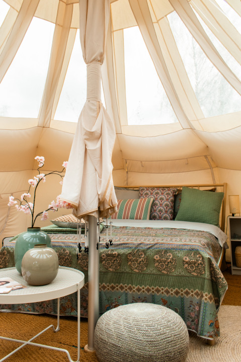 Sfeervol ingerichte Lotus Belle tent met tweepersoonsbed en kussens in Recreatiepark De Achterste Hoef.
