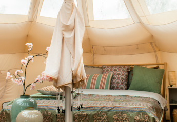 Gemütlich eingerichtetes Lotus Belle Zelt mit Doppelbett und Dekokissen im De Achterste Hoef Park.