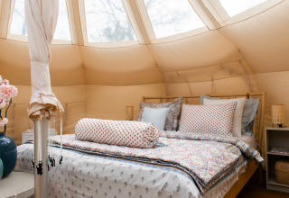 Innenaufnahme eines gemütlichen Lotus Belle Safari-Zeltes mit Doppelbett und stilvoller Einrichtung.