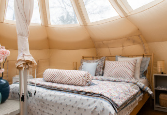Innenaufnahme eines gemütlichen Lotus Belle Safari-Zeltes mit Doppelbett und stilvoller Einrichtung.