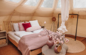 Interieur van een Lotus Belle safaritent in Recreatiepark De Achterste Hoef, Nederland, met gezellig bed.