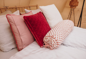 Bett mit bunten Kissen und Bolster im Lotus Belle Safarizelt im Erholungspark De Achterste Hoef, Niederlande.