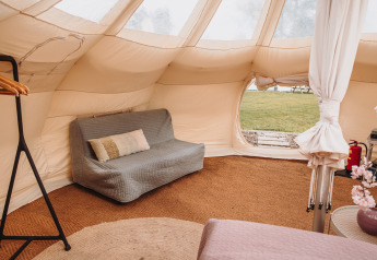 Innenraum des Lotus Belle Safarizeltes im Erholungspark De Achterste Hoef in den Niederlanden mit Sofa und Teppich.