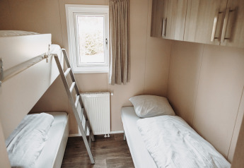 Helles Zimmer mit Etagenbett und Einzelbett im Luxus-Chalet im Erholungspark De Achterste Hoef, Niederlande.