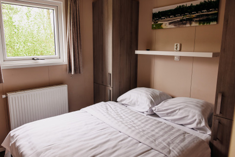 Bedroom in a luxury chalet at Recreation Park De Achterste Hoef, Netherlands, featuring bed and window.