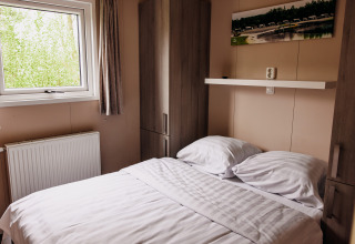Bedroom in a luxury chalet at Recreation Park De Achterste Hoef, Netherlands, featuring bed and window.