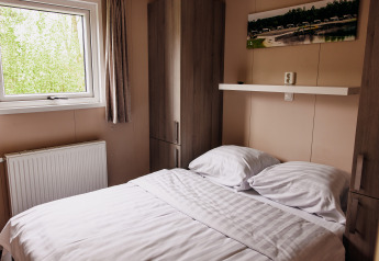 Bedroom in a luxury chalet at Recreation Park De Achterste Hoef, Netherlands, featuring bed and window.