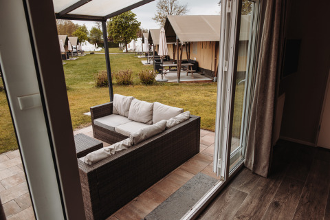 Vue d'un chalet de luxe au parc De Achterste Hoef aux Pays-Bas avec canapé extérieur et terrasse.
