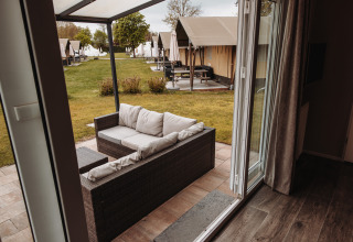 Vue d'un chalet de luxe au parc De Achterste Hoef aux Pays-Bas avec canapé extérieur et terrasse.