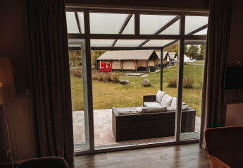 View from a luxury chalet at Recreation park De Achterste Hoef, Netherlands, patio seating and tents outside.