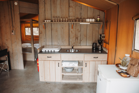 Kitchen area inside a safari tent at Recreation park De Achterste Hoef, Netherlands, with rustic wood decor.