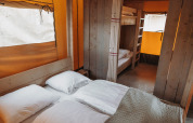 Innenansicht eines Safari-Zeltes mit Doppelbett und Etagenbetten im Ferienpark De Achterste Hoef, Niederlande.