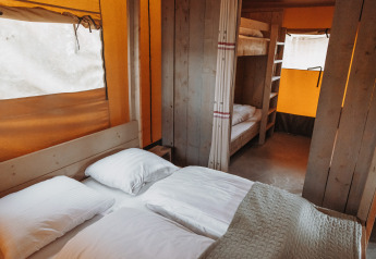Innenansicht eines Safari-Zeltes mit Doppelbett und Etagenbetten im Ferienpark De Achterste Hoef, Niederlande.