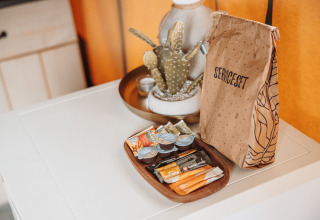 Service set and snacks on a white table inside a safari tent at Recreation Park De Achterste Hoef, Netherlands.