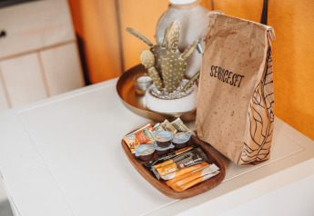 Service-Set und Snacks auf einem weißen Tisch im Safarizelt im Freizeitpark De Achterste Hoef, Niederlande.