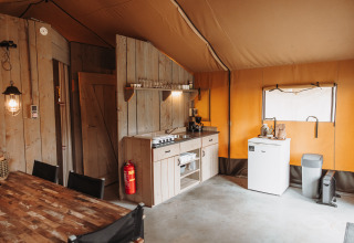 Interior de una tienda safari con cocina, nevera y mesa en Recreation park De Achterste Hoef, Países Bajos.