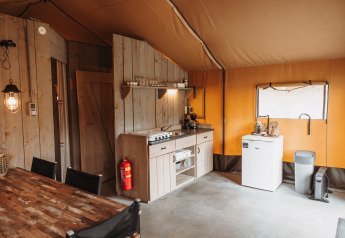 Innenraum eines Safarizelts mit Küche, Kühlschrank und Esstisch im Recreation Park De Achterste Hoef, Niederlande.