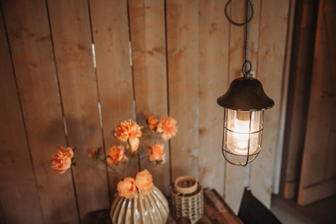 Lampe suspendue et vase à fleurs sur table en bois sous tente safari au parc De Achterste Hoef, Pays-Bas.