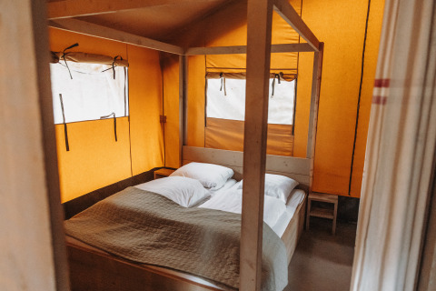 Innenaufnahme eines Safari-Zeltes im Freizeitpark De Achterste Hoef in den Niederlanden mit Bett und Kissen.