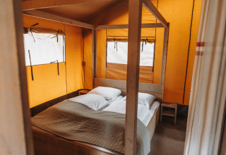Innenaufnahme eines Safari-Zeltes im Freizeitpark De Achterste Hoef in den Niederlanden mit Bett und Kissen.