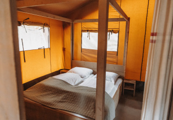 Interior view of safari tent at Recreation park De Achterste Hoef in the Netherlands, featuring a cozy bed.