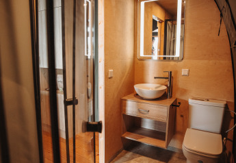 Modernes Badezimmer mit Holzwänden, rundem Waschbecken, beleuchtetem Spiegel und WC in Water lodge.