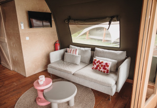 Gemütliches Wohnzimmer mit grauem Sofa und bunten Kissen in der Water lodge im De Achterste Hoef Park.