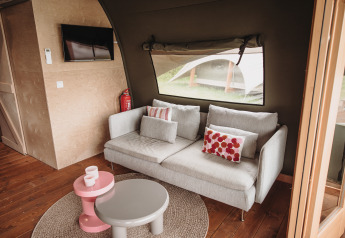 Gemütliches Wohnzimmer mit grauem Sofa und bunten Kissen in der Water lodge im De Achterste Hoef Park.