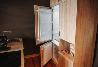Küche mit offenem Kühlschrank und Gefrierfach in der Water Lodge im Freizeitpark De Achterste Hoef, Niederlande.