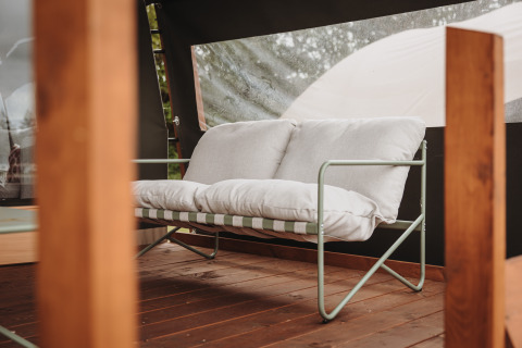 Sofá cómodo con cojines blancos en la terraza de madera de Water lodge en De Achterste Hoef, Países Bajos.