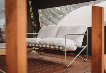 Canapé confortable avec coussins blancs sur une terrasse en bois à la Water lodge de De Achterste Hoef, Pays-Bas.