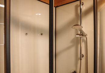 Modern shower enclosure with glass doors in Water lodge at Recreation park De Achterste Hoef, Netherlands.