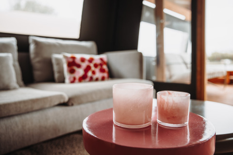 Living area in the Water lodge at De Achterste Hoef with gray sofa and pink candles on a round table.