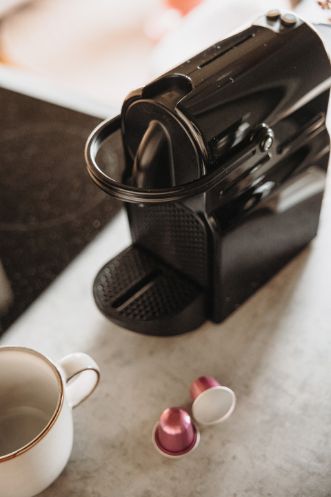 Schwarze Kaffeemaschine mit Tasse und Kapseln auf der Theke, Water lodge im De Achterste Hoef, Niederlande.