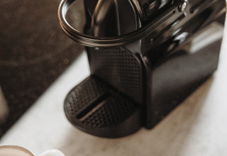 Schwarze Kaffeemaschine mit Tasse und Kapseln auf der Theke, Water lodge im De Achterste Hoef, Niederlande.