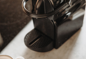 Black coffee machine, white cup, and coffee pods on a counter at Water lodge, De Achterste Hoef, Netherlands.