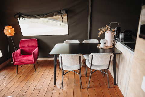 Modernes Lodge-Interieur mit rotem Sessel, schwarzem Esstisch und vier hellen Stühlen in den Niederlanden.