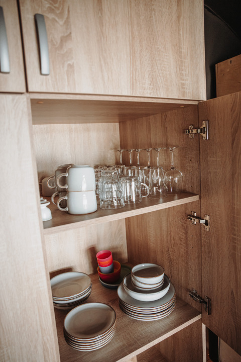 Placard ouvert avec assiettes, tasses et verres à la Water lodge du parc De Achterste Hoef aux Pays-Bas.