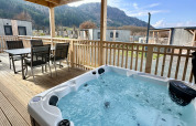 Outdoor terrace at Enzian lodge, Ossiacher See, Austria, featuring a hot tub and mountain views.