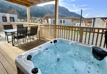 Terrasse extérieure à la lodge Enzian au lac Ossiacher, Autriche, avec jacuzzi et vue sur les montagnes.