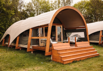 Komfortabel og moderne Water Lodge med trækonstruktion og overdækket terrasse placeret i grønt område.