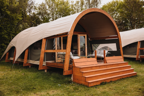 Komfortabel og moderne Water Lodge med trækonstruktion og overdækket terrasse placeret i grønt område.