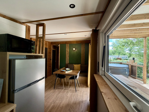 Interior view of a lodge at La Clairiere, Campsite Seasonova Ensoya, France, showing dining table and outdoor deck.