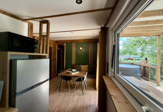 Indvendig udsigt over en lodge ved La Clairiere på Campsite Seasonova Ensoya, med spisebord og terrasse udenfor.