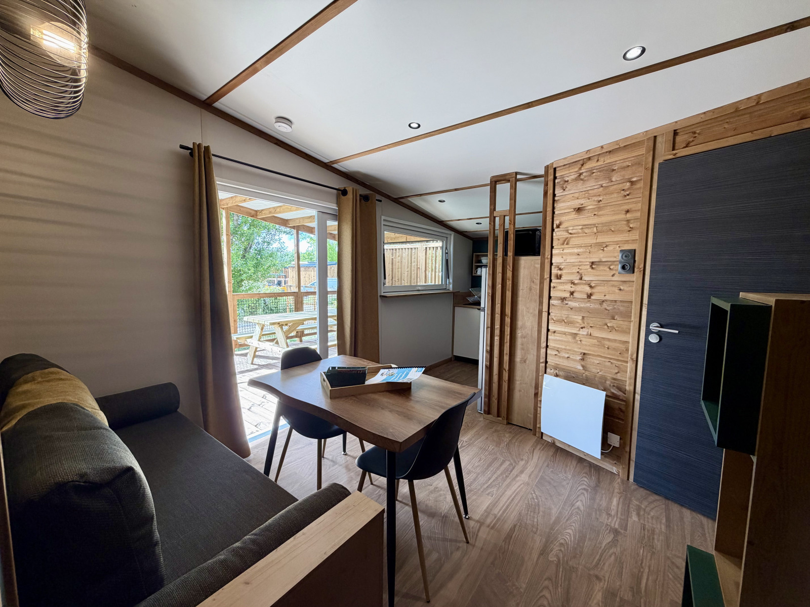 Interieur van een lodge bij La Clairiere, Campsite Seasonova Ensoya, Frankrijk, met eethoek en terraszicht.