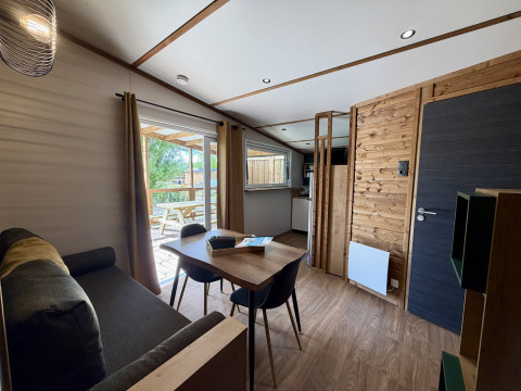 Interno di un lodge a La Clairiere, Campeggio Seasonova Ensoya, Francia, con zona pranzo e vista terrazza.